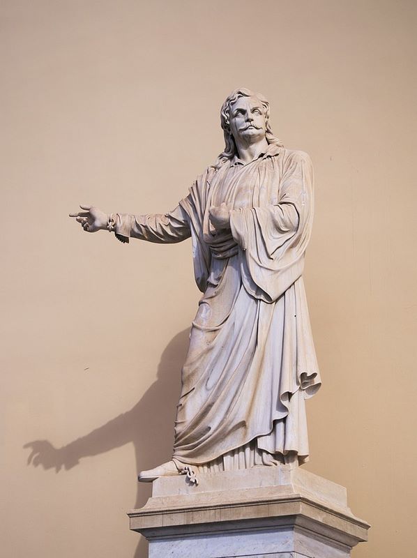 Ο Ρήγας Βελεστινλής, αριστερά της εισόδου του Πανεπιστημίου Αθηνών. Ανεγέρθηκε το 1871 με δαπάνη του Γεωργίου Αβέρωφ. Έργο του γλύπτη Ι. Κόσσου